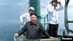 Chủ tịch Bắc Hàn Kim Jong Un đứng trên một chiếc tàu ngầm trong khi thị sát một đơn vị hải quân hôm 14/6/2014.